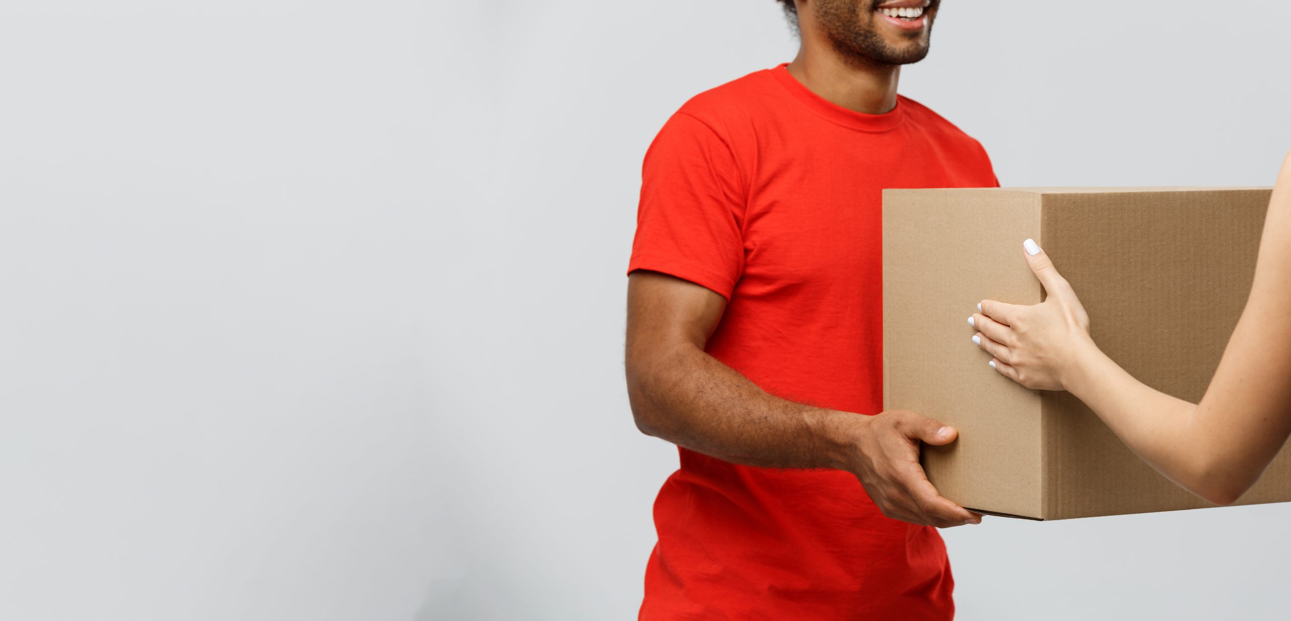 Delivery Concept - Handsome African American delivery man giving package to homeowner. Isolated on Grey studio Background. Copy Space